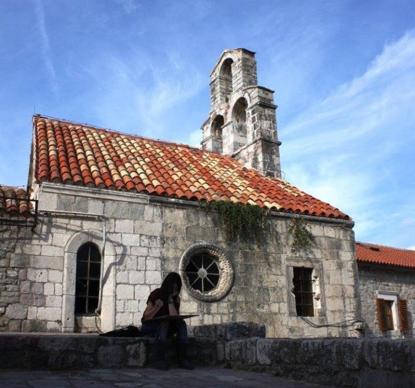 Neslihan Albayrak tarihi taş kilise önünde defterine yazı yazarken